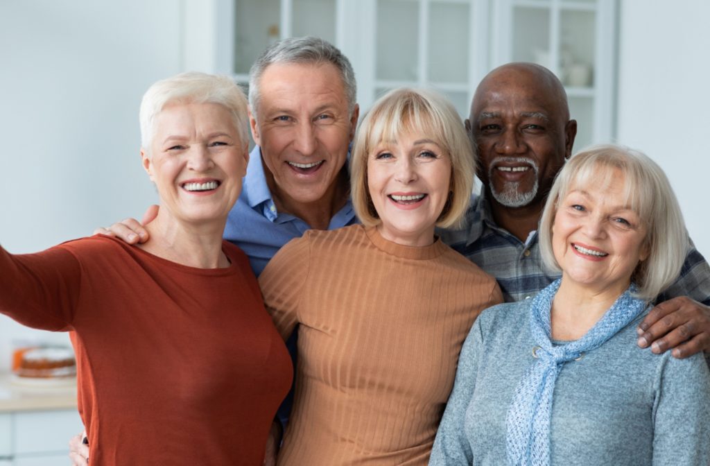 A group of happy older adults take a picture together in a senior living community.