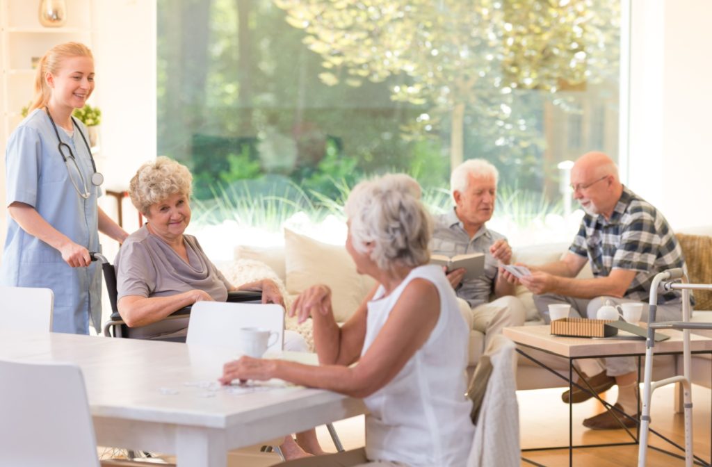 Several residents hang out in a well-lit shared living space of their assisted living community