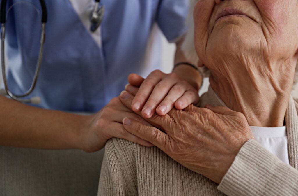 A doctor reaches out and places their hands on their senior patient's shoulder after giving them a dementia diagnosis.